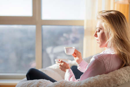 Woman relaxing at home and drinking teaの写真素材