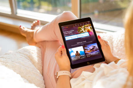 Riga, Latvia - July 21, 2018: Woman looking at Momondo cheap flight search website on iPad.のeditorial素材