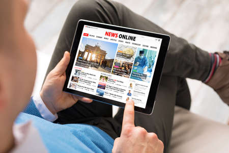 Man reading daily news online on tabletの写真素材