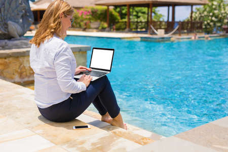 Business lady working on computer by the poolの写真素材