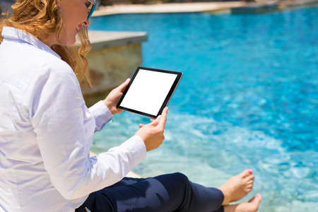 Business woman using tablet computer by the poolの写真素材