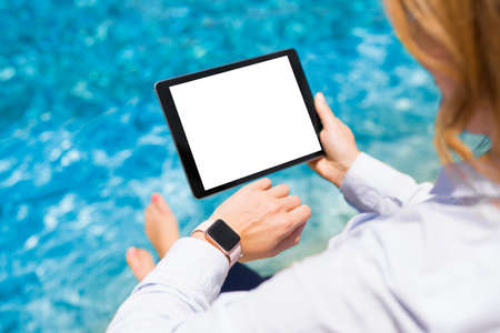 Woman using modern technology gadgets on vacation by the poolの写真素材