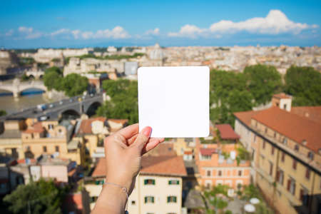 Person holding blank white paper in front of cityの写真素材