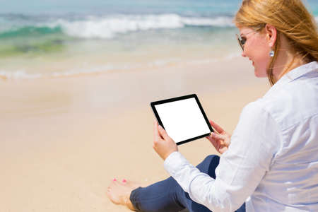 Business person with tablet on the beachの写真素材