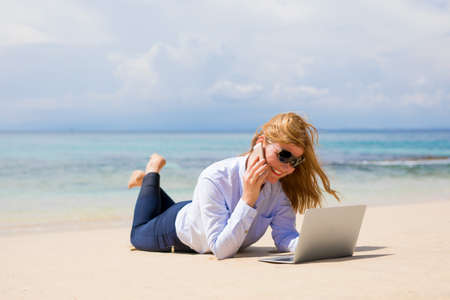 Busy woman enjoying working from the beachの写真素材
