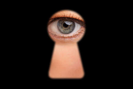 Eye of person looking through keyhole in doorsの写真素材