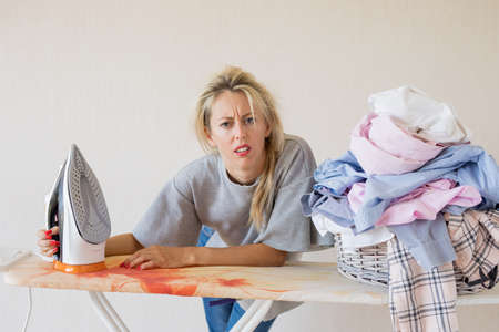 Tired and exhausted woman at ironing deskの写真素材