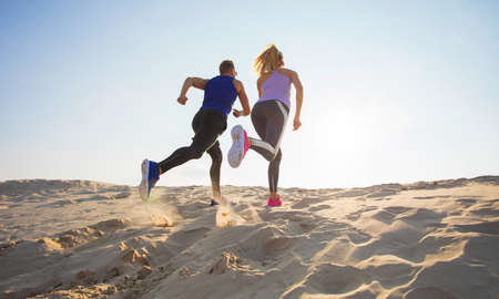 Man and woman running in sandの写真素材