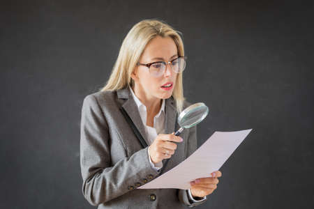 Woman carefully reading business contract with magnifying glassの写真素材