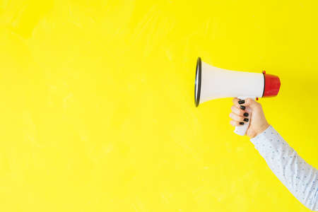Person holding megaphone on empty yellow backgroundの写真素材