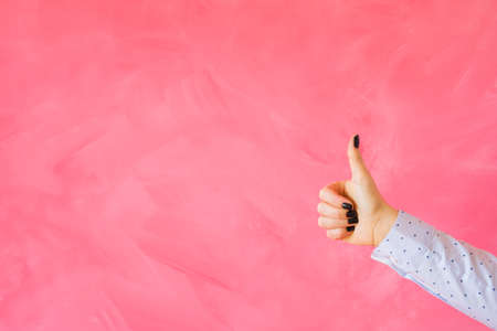 Person showing thumbs up hand gesture on empty pink backgroundの写真素材