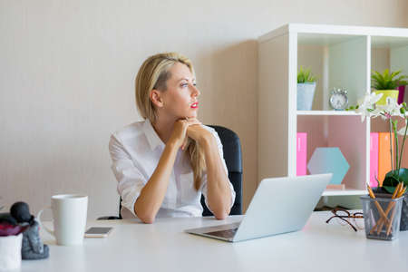 Serious looking woman thinking about something at workplaceの写真素材