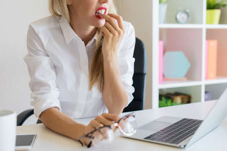 Nervous woman at work biting her nailsの写真素材