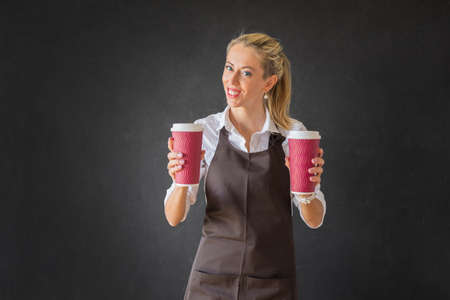 Barista holding two cups of coffee on dark backroundの写真素材