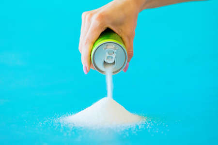 Person pouring sugar out of soft drink canの写真素材