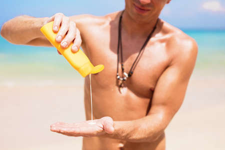 Man using sunscreen product to protect skin from uv rays at beachの写真素材