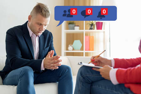 Man visiting psychologist and feeling depressed about his unpopularity on social mediaの写真素材