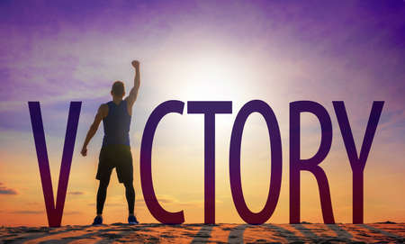 Man celebrating success. Victory text and person as silhouettes against sun in sky.の写真素材