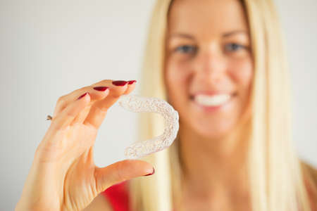 Woman with beautiful smile holding teeth whitening trayの写真素材