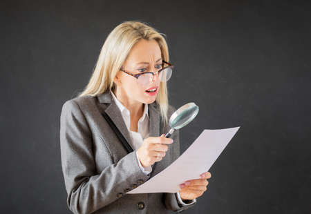 Woman reading business contract with magnifying glassの写真素材