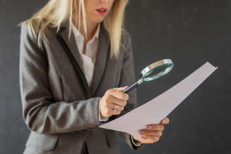 Woman carefully reading business contract with magnifying glassの写真素材