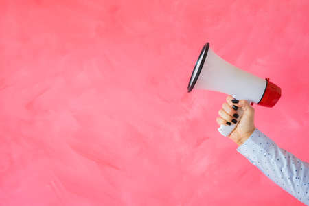 Person holding megaphone on empty pink backgroundの写真素材