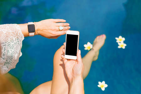 Woman using smart digital tech by the poolの写真素材