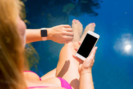 Woman using smart digital tech by the poolの写真素材