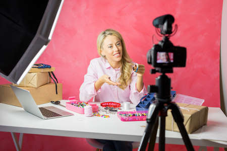 Social media influencer young woman recording video blog with instructional how-to tutorial for making your own jewellery.の写真素材