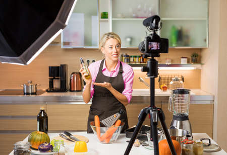 Woman recording video in her home kitchen, creating content for video blogの写真素材