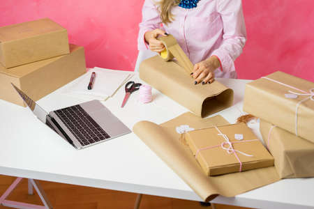 Woman selling items online and packaging goods for shipping.の写真素材