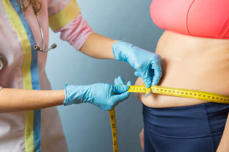 Doctor taking obese woman's body fat measurementsの写真素材