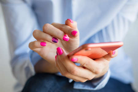 Woman holding mobile phone in hands, close-up photoの写真素材