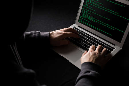 Hacker working on computer code in the darkの写真素材
