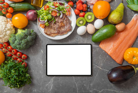 Tablet computer on a kitchen counter surrounded by low carb productsの写真素材