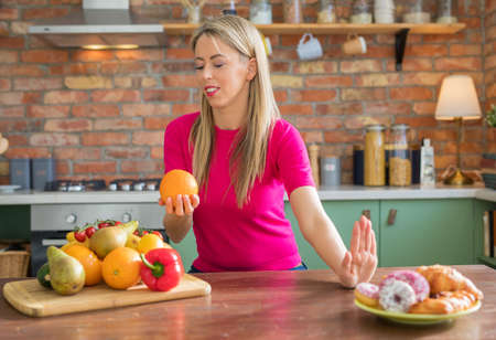 Woman choosing to eat healthy and fresh fruits versus bad unhealthy onesの写真素材