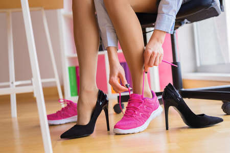 Woman changing heels to comfortable shoes in the officeの写真素材