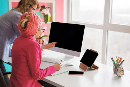 Two female colleagues working in the office and looking at computer screenの写真素材