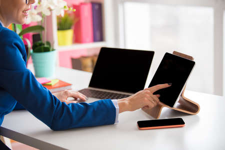 Woman working in the office and using different tech devicesの写真素材