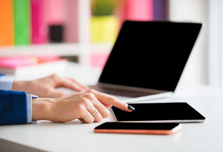 Woman working in the office and using laptop, tablet and mobile phoneの写真素材