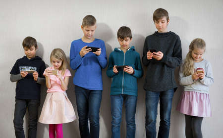 Portrait of positive kids playing with their phonesの写真素材