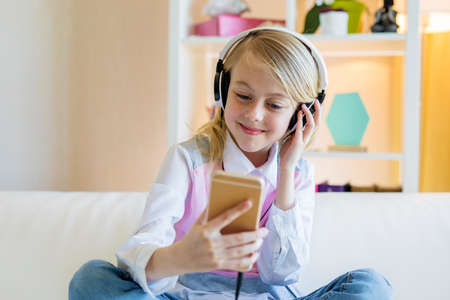 Happy teenager girl using smartphone and headphones, listening to musicの写真素材