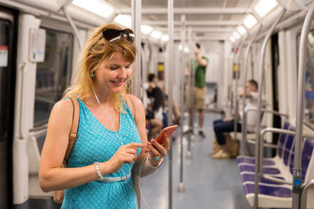 Woman riding in metro and using mobile phoneの写真素材