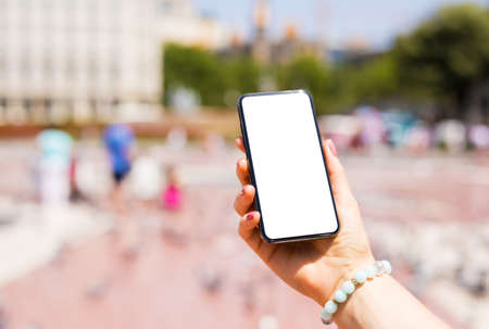 Person holding smartphone outdoors in the city, phone mockup with empty white screen.の写真素材