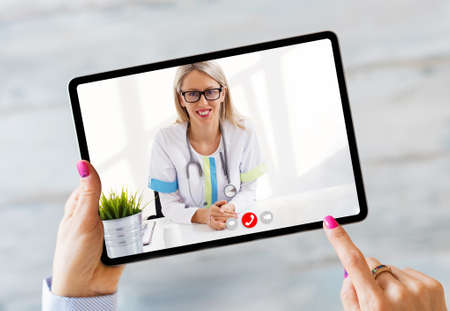 Person talking with doctor on video call on tablet computerの写真素材