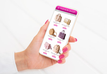 Woman browsing bags to buy in online shop on her mobile phoneの写真素材