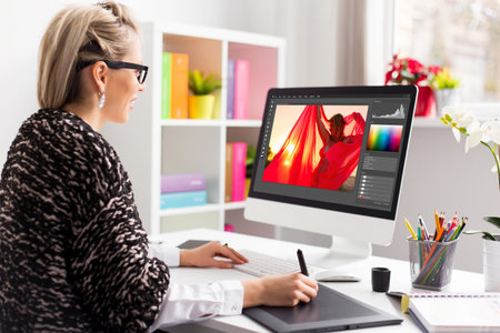 Woman editing photo on computer. Software interface is completely made up.の写真素材