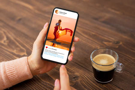 Woman looking at photo of beautiful female model on mobile phoneの写真素材