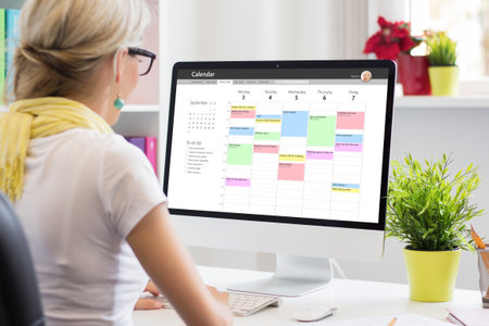 Woman using calendar app on computer in officeの写真素材