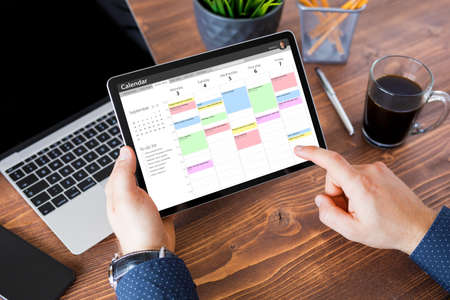 Man using calendar app on tablet at workの写真素材